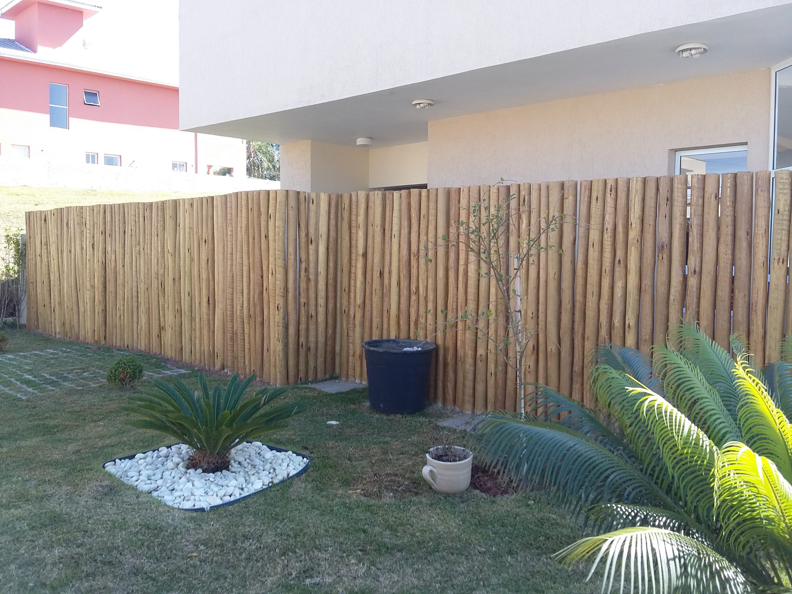 Muro de eucalipto tratado roliço instalado para privacidade em jardim residencial