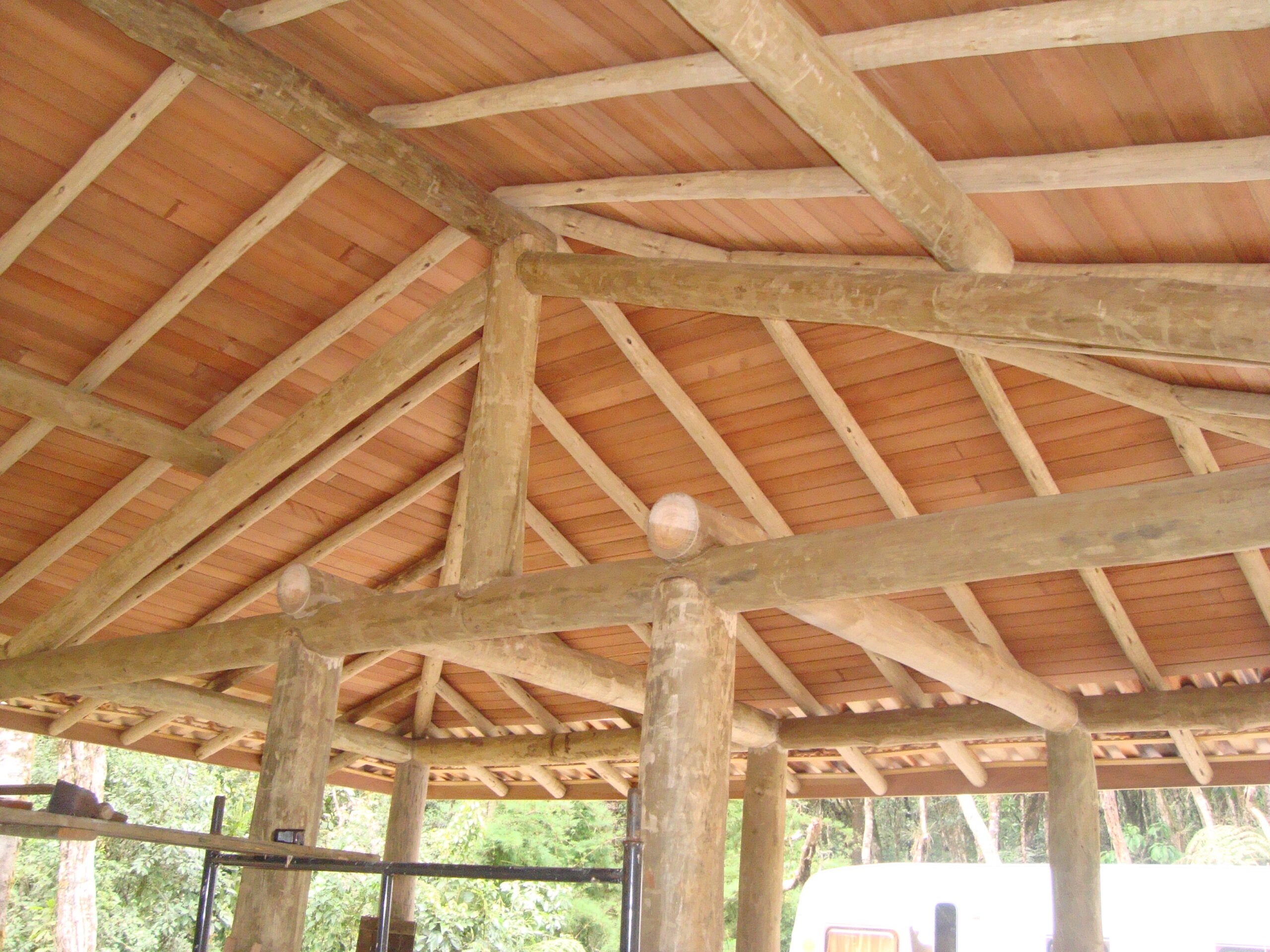 Vista interna de telhado rústico com forro instalado sobre a estrutura